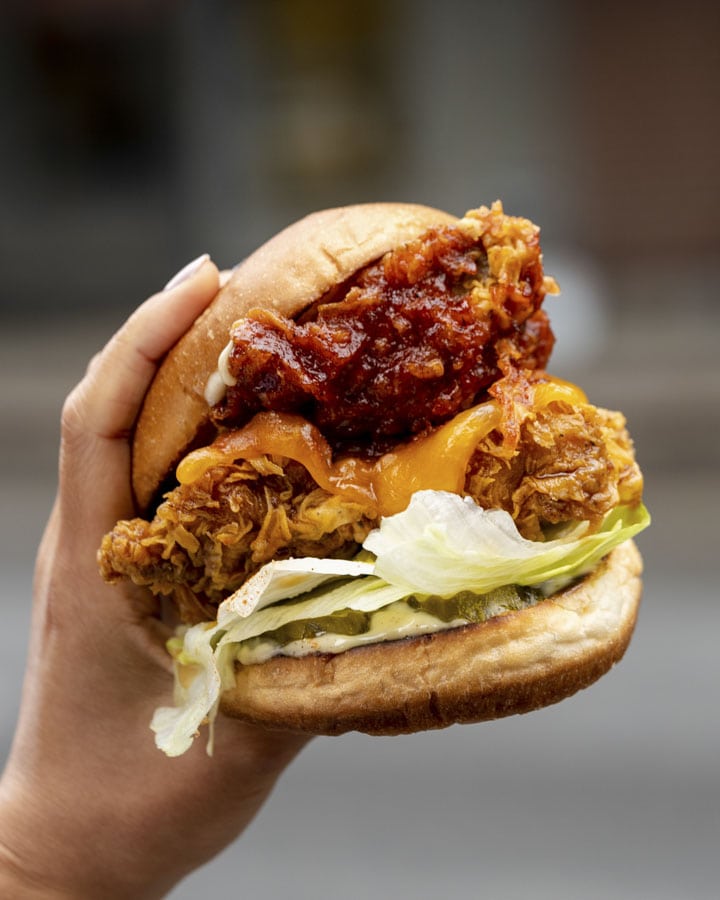 Double-Decker Sandwich - a feature that sees two boneless fried chicken thighs – one slathered with sweet soy sauce, the other in yang nyeom sauce –lettuce, marble cheese and house mayo stacked between two toasted buns  