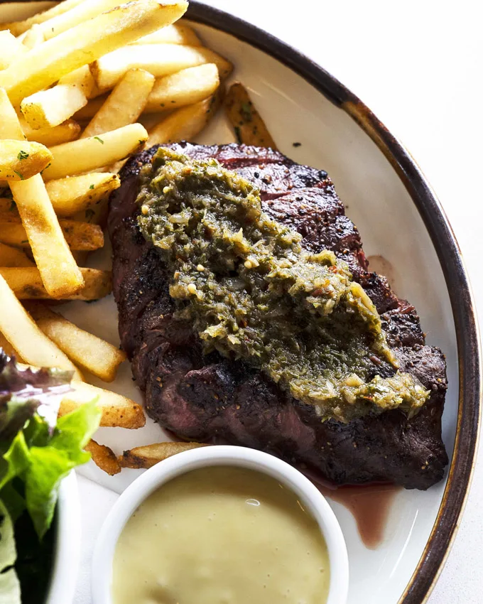 A 6oz flat iron grilled steak with caramelized garlic aioli, pickled ramp chimichurri and red wine demi glace accoutrements.